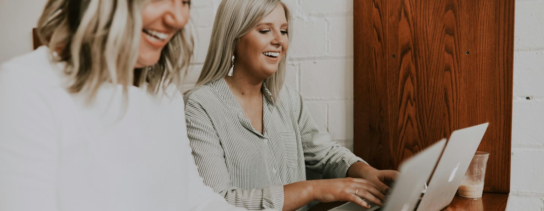 a couple of women looking at a laptop
